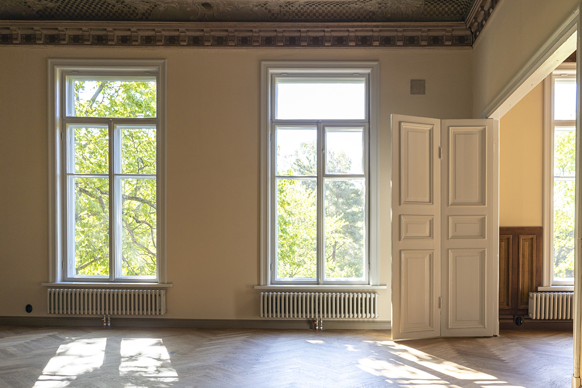 Inside Puistokatu 4 with wooden floors and big windows showing the Kaivopuisto park